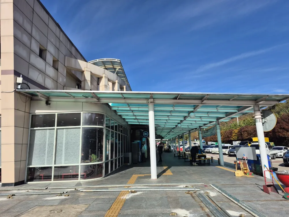 건축물철거과정 중 유리 출입구와 캐노피가 있는 건물 정면과 인접 통행 구간
